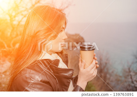 Woman coffee sunset young lady in leather jacket holding a paper cup and looking at the ocean at dusk with copy space Woman coffee sunset young lady in leather jacket holding a paper cup and looking at the ocean at dusk with copy space 139763891