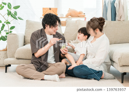 A boy eats vegetable sticks as a snack or light meal with his parents and family. A boy eats vegetable sticks as a snack or light meal with his parents and family. 139763937