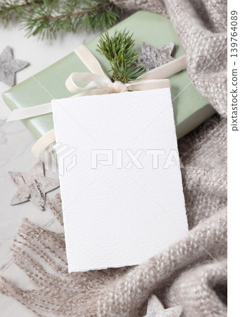 Christmas card mockup on wrapped sage green gift box with ribbon bow and fir branch, top view Christmas card mockup on wrapped sage green gift box with ribbon bow and fir branch, top view 139764089