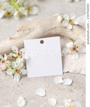 Blank square gift tag mockup with white spring flowers and driftwood on light stone, label design Blank square gift tag mockup with white spring flowers and driftwood on light stone, label design 139764093