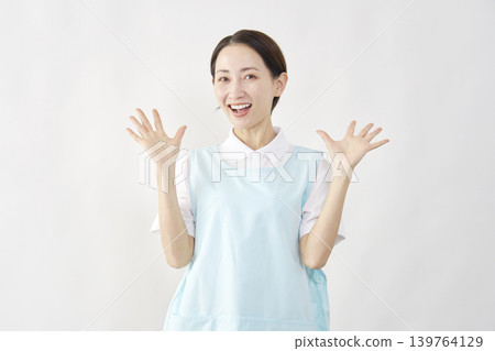 A female caregiver smiles in surprise against a white background. 139764129
