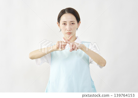女護理員在白色背景前擺出「X」形姿勢。 139764153