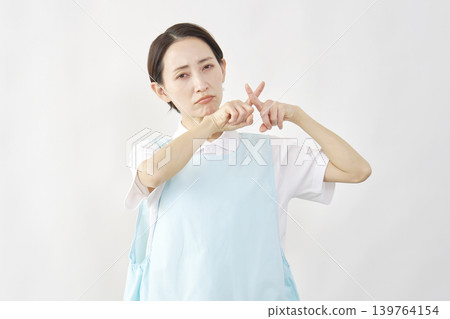 女護理員在白色背景前擺出「X」形姿勢。 139764154