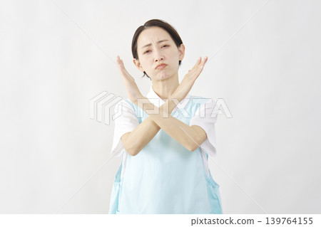Female caregiver making an "X" pose against a white background. Female caregiver making an "X" pose against a white background. 139764155