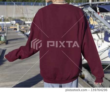 Blank dark red oversized unisex sweatshirt mockup on woman near boats and yachts, back copy space Blank dark red oversized unisex sweatshirt mockup on woman near boats and yachts, back copy space 139764296