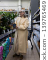 Senior woman smiling while holding a potted plant in a garden store 139765469