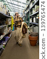 Woman shopping for flower pots and plant supplies, talking on her mobile phone 139765474