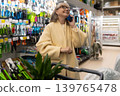 Mature woman talking on smartphone while pushing a shopping cart in a retail store 139765478