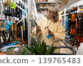 Senior woman shopping for new horticulture equipment in a retail store aisle 139765483