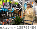 Senior woman smiling, holding gardening tools, standing by shelves in a hardware store 139765484