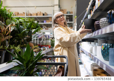 Senior woman shopping for new flowerpots in a retail garden center Senior woman shopping for new flowerpots in a retail garden center 139765488