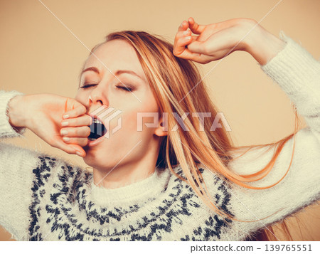 Sleepy yawning teenage woman in jumper Sleepy yawning teenage woman in jumper 139765551