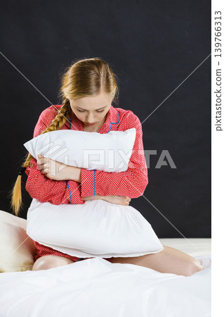 Sad depressed girl in bed gripping pillow Sad depressed girl in bed gripping pillow 139766313