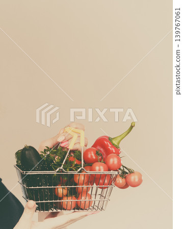 Hand holds shopping cart with vegetables Hand holds shopping cart with vegetables 139767061