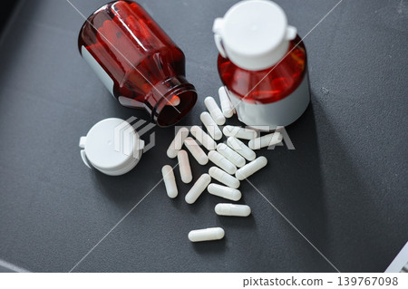 Unlabeled Pill Bottles and White Medicine Capsules on Black Table. Unlabeled Pill Bottles and White Medicine Capsules on Black Table. 139767098