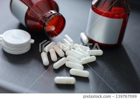 Unlabeled Pill Bottles and White Medicine Capsules on Black Table. Unlabeled Pill Bottles and White Medicine Capsules on Black Table. 139767099