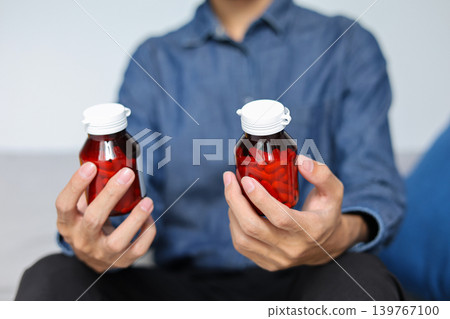 Man Holding Two Medicine Bottles Comparing Prescription Medicine Bottles in Hand. Man Holding Two Medicine Bottles Comparing Prescription Medicine Bottles in Hand. 139767100