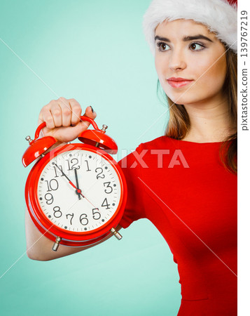 Woman wearing Santa Claus costume holding clock 139767219