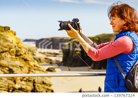 Woman with camera at Cathedral Beach in Spain. Woman with camera at Cathedral Beach in Spain. 139767324