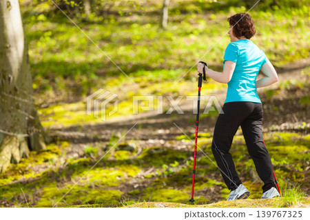Nordic walking. Woman hiking in the forest park. Nordic walking. Woman hiking in the forest park. 139767325