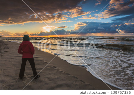 Woman enjoying dramatic sunset on sea Woman enjoying dramatic sunset on sea 139767326