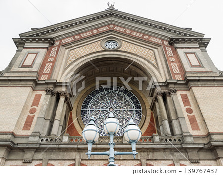 An low-angle view the magnificent Victorian architecture of Alexandra Palace Great Hall facade. The structure is an exquisite tapestry of pale cream and rich terracotta brickwork, striking a perfect An low-angle view the magnificent Victorian architecture of Alexandra Palace Great Hall facade. The structure is an exquisite tapestry of pale cream and rich terracotta brickwork, striking a perfect 139767432
