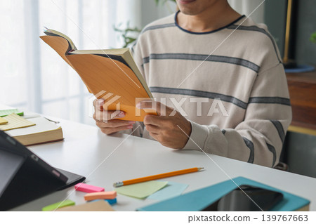 Man in casual cloth reading, studying at home. Man in casual cloth reading, studying at home. 139767663