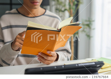 Man in casual cloth reading, studying at home. Man in casual cloth reading, studying at home. 139767664