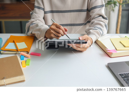 Man organizing schedule with sticky notes and digital tablet at home. Man organizing schedule with sticky notes and digital tablet at home. 139767665