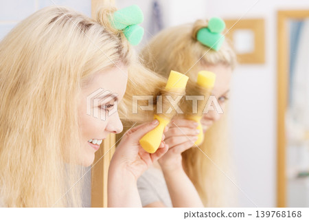 Blonde woman using hair rollers 139768168