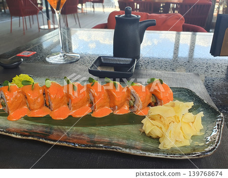Gourmet Sushi Roll with Spicy Sauce and Pickled Ginger on Elegant Ceramic Plate 139768674