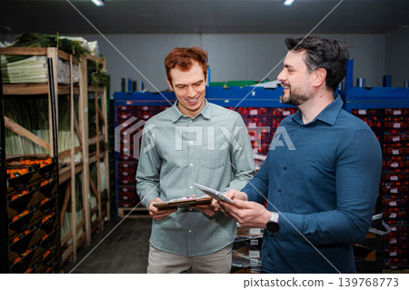 Two men at work in a food distribution warehouse, checking inventory 139768773