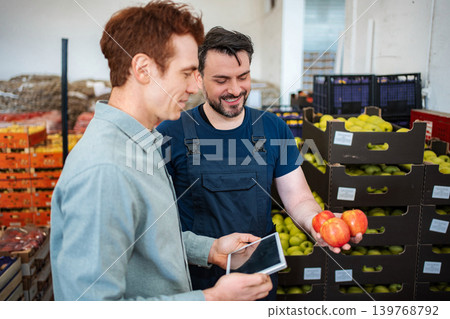 Worker showing fresh apples to customer in warehouse Worker showing fresh apples to customer in warehouse 139768792