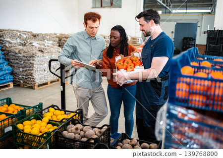 Employees discussing fresh produce inventory in a food warehouse Employees discussing fresh produce inventory in a food warehouse 139768800