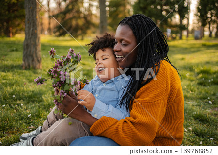 African american mother, son picking flowers in park African american mother, son picking flowers in park 139768852