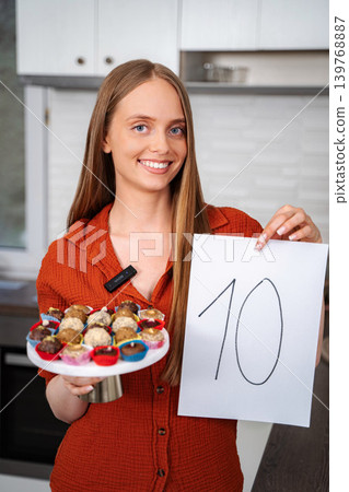 Woman holding tray of desserts and number ten sign Woman holding tray of desserts and number ten sign 139768887