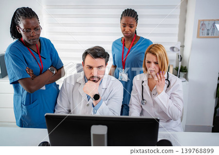 Medical team collaborating on a difficult diagnosis reviewing computer data 139768899