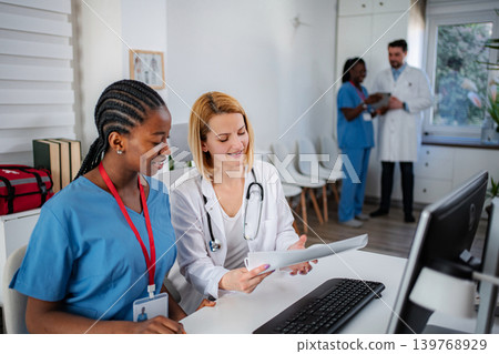 Female medical professionals collaborating on patient records in clinic Female medical professionals collaborating on patient records in clinic 139768929