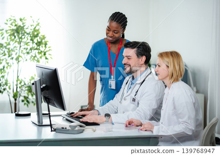 Medical team collaborating on computer in clinic office 139768947