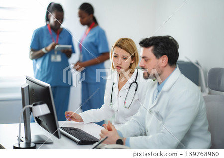 Medical team collaborating online in hospital using computer Medical team collaborating online in hospital using computer 139768960