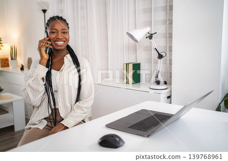 Young woman smiling, talking on phone, working from home Young woman smiling, talking on phone, working from home 139768961