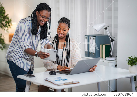 Young black businesswomen collaborating on a project in a modern office Young black businesswomen collaborating on a project in a modern office 139768964