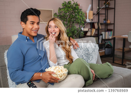 Happy couple relaxing at home watching movie eating popcorn Happy couple relaxing at home watching movie eating popcorn 139768989