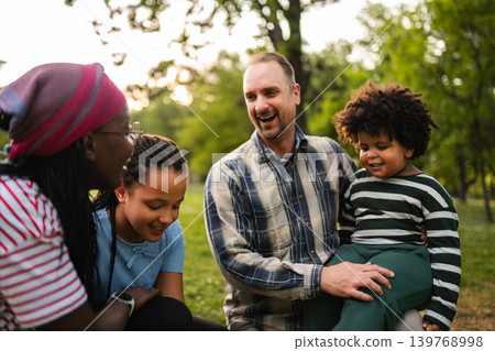 Multiracial family laughing together spending time outdoors in park 139768998
