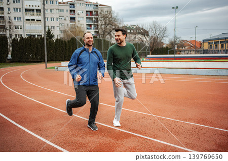 Two men friends jogging on running track Two men friends jogging on running track 139769650