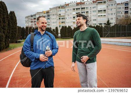Two friends laughing on running track after exercise Two friends laughing on running track after exercise 139769652