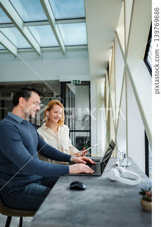 Professionals collaborating on laptop and digital tablet in modern office Professionals collaborating on laptop and digital tablet in modern office 139769686
