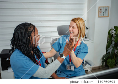 Medical professionals high fiving celebrating teamwork success in office Medical professionals high fiving celebrating teamwork success in office 139769693