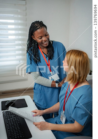 Diverse nurses collaborating on paperwork in modern office Diverse nurses collaborating on paperwork in modern office 139769694