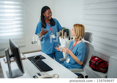 Diverse nurses collaborating and discussing in hospital office during break Diverse nurses collaborating and discussing in hospital office during break 139769697